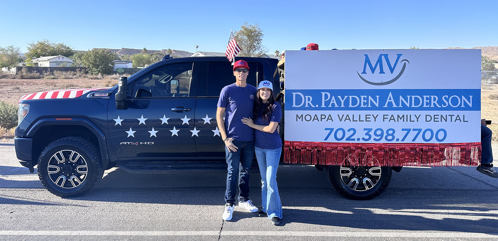 A person stands next to a large truck with an advertisement, which includes a phone number and a website address for dental services.